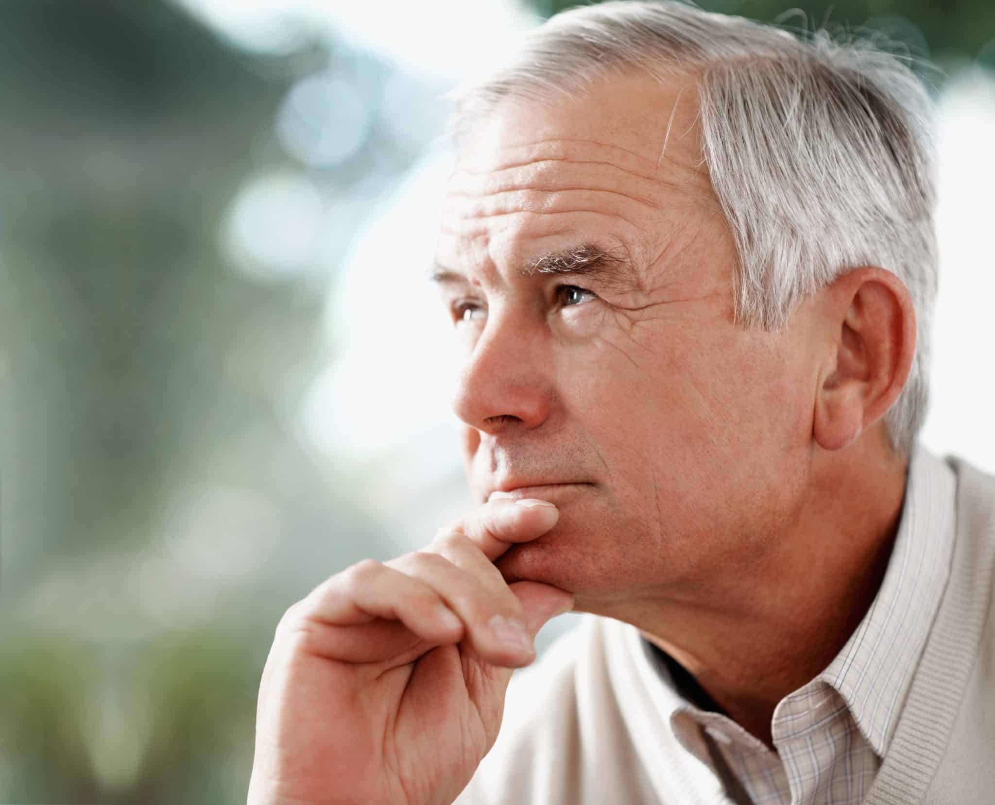 Man with depression and hearing loss Contemplative senior man with hearing loss looking away