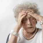 Older woman with her hands on her forehead in a stressed out manner