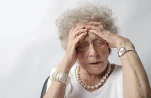 Older woman with her hands on her forehead in a stressed out manner