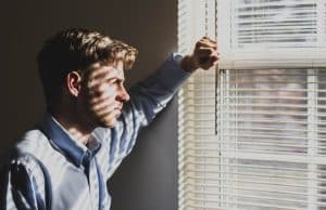 Depressed man looking outside of a window.