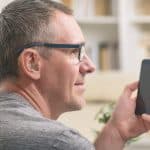 Man with hearing aids uses a smartphone.