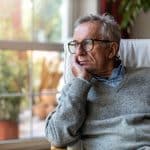 Older man looking out the window of his home.
