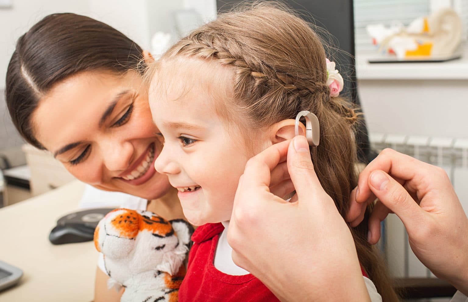 Audiologist fitting a child with a new hearing aid