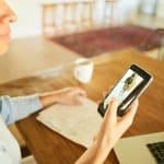 Woman getting a video notification on an app on her smart phone of someone at her front door while working at home