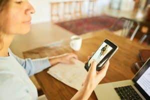 Woman getting a video notification on an app on her smart phone of someone at her front door while working at home