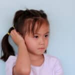 Young girl covers ear with hand