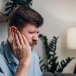 Man with tinnitus holding his ear