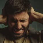 Man covering his ears because of loud noise