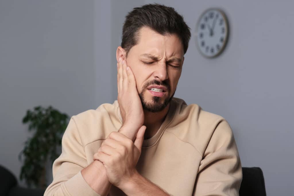 Man with tinnitus holding his ear.