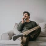 Man talking on his phone while sitting on his couch.