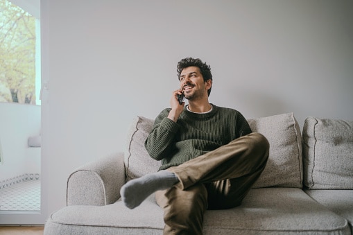 Man talking on his phone while sitting on his couch.