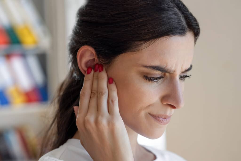 Woman with tinnitus holds hand over ear