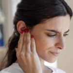Woman with tinnitus holds hand over ear