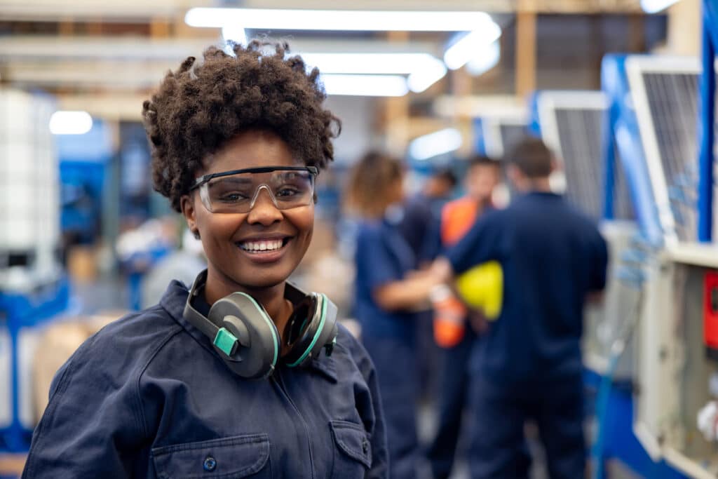 Happy employee with earmuffs working at a solar panel factory.