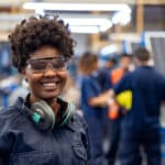 Happy employee with earmuffs working at a solar panel factory