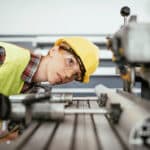 Woman with protective equipment working on the drill in factory plant