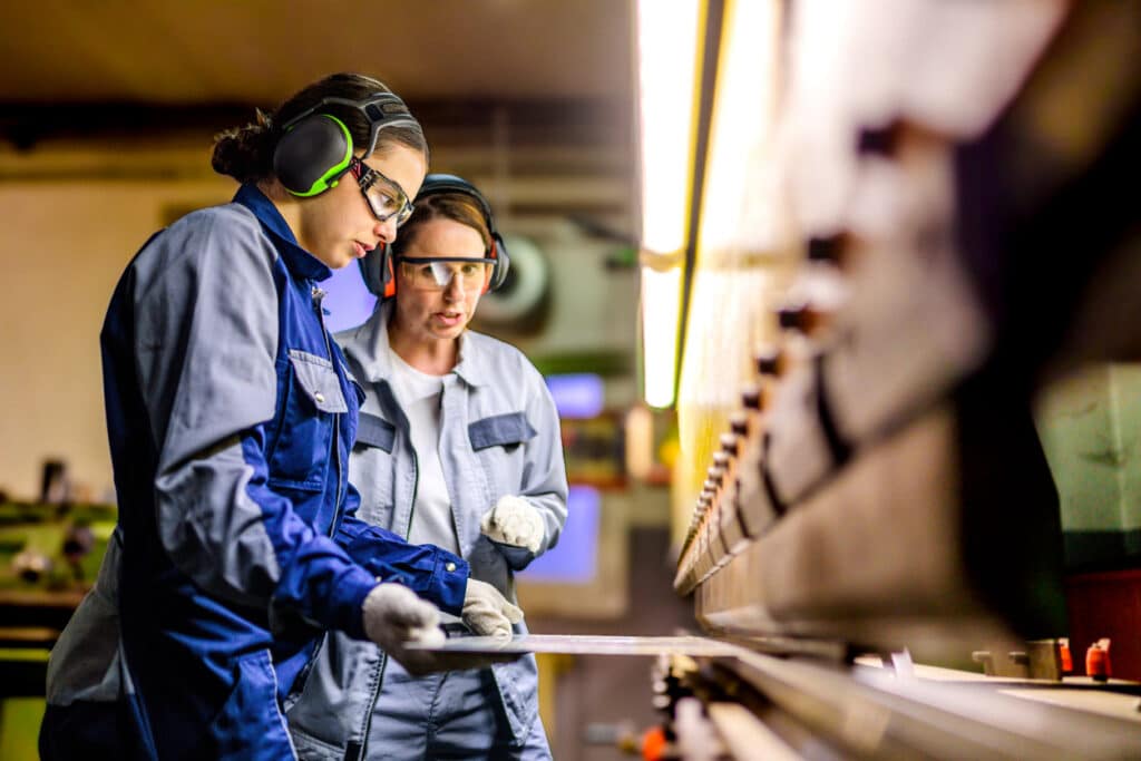 Factory workers wearing hearing protection and eyeware.