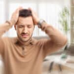 Man with tinnitus holding his head, blurred effect.