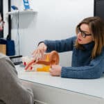 Audiologist showing ear model to patient and explaining his condition