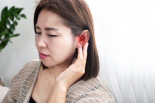 Woman holding her sore, red ear.