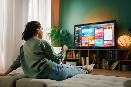 Happy woman watching TV at home.