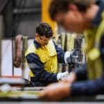 Qualified welders working on steel construction, grinding and welding iron parts in modern bright warehouse