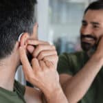 Happy man putting on his hearing aid.