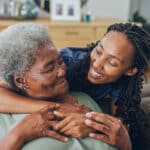 Young woman hugging her senior mother at home.