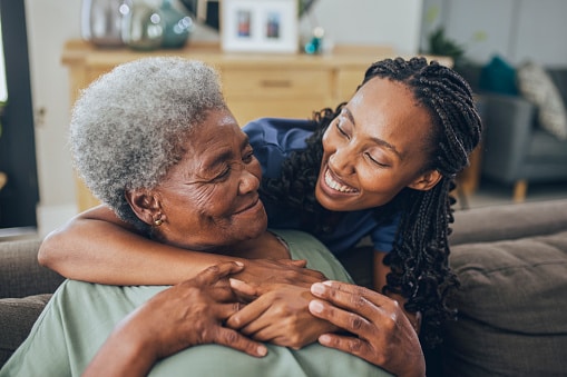 Young woman hugging her senior mother at home.