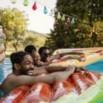 Group of friends sitting on pool floating in the pool.