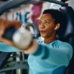 Woman doing weight exercises for upper body strength during sports training in a gym.