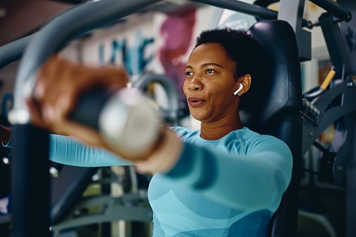 Woman doing weight exercises for upper body strength during sports training in a gym.